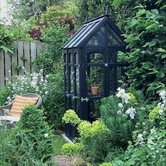 a small black gazebo surrounded by greenery and flowers