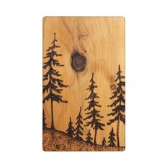 a wooden plaque with trees on it and a hole in the wood that is carved to look like a forest