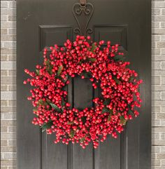 a red berry wreath hangs on the front door