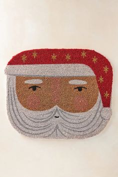 a door mat with a santa claus face on it and stars around the beard,