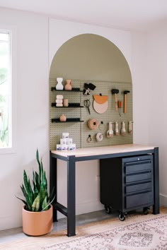 a room with a desk and shelves on the wall next to a potted plant