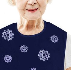 an older woman with white hair wearing a blue top and smiling at the camera while standing in front of a white background