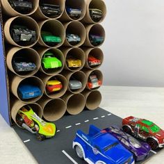 two toy cars are parked next to each other in front of a cardboard tube holder