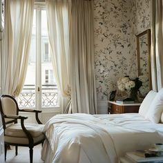 a white bed sitting next to a window in a room with curtains on the windowsill