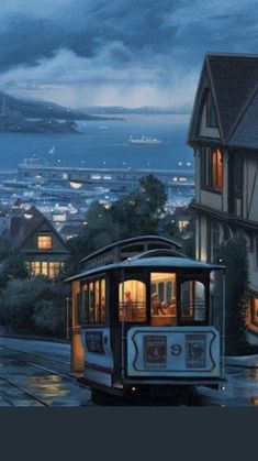 a trolley car is traveling down the street in front of some houses and buildings at night