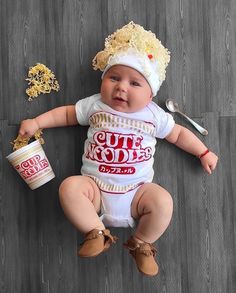 a baby is sitting on the floor with some food in it's hands and wearing a hat