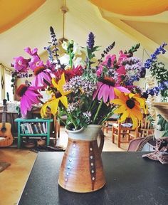 a vase filled with lots of colorful flowers on top of a table next to a guitar