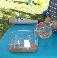 a young boy sitting at a table with a baseball bat and glass bowl on it