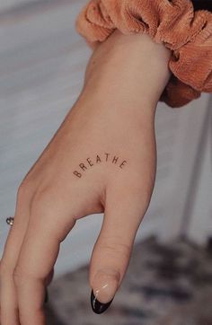 a woman's hand with the word breathe tattooed on it