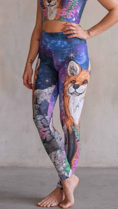 Girl wearing WERKSHOP X Save A Fox Athleisure Leggings. The artwork on the leggings features a coy red fox looking upward while perched on a rock and framed with foxglove flowers. The background for the artwork features a galactic sky with swirls of purple and blue and sparkling stars. Stretch Athleisure Sweatpants For Outdoor, Stretch Sportswear Sweatpants For Outdoor Activities, Relaxed Fit Athleisure For Outdoor Activities, Relaxed Fit Activewear For Outdoor Activities, Relaxed Fit Sportswear For Outdoor Activities, Casual Full-length Activewear For Outdoor, Sporty Moisture-wicking Yoga Pants For Outdoor Activities, Stretch Joggers For Outdoor Activities, Athleisure Stretch Sweatpants For Outdoor Activities