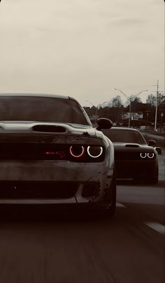 the front end of a car driving down a road with other cars in the background