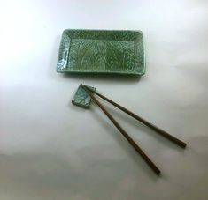 two chopsticks and a green tray on a table