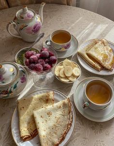 a table topped with plates of food and cups of tea