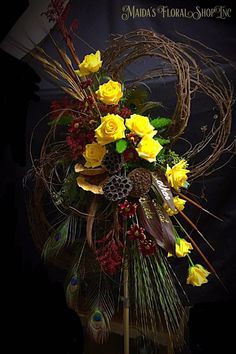 a vase with yellow flowers and feathers on it's head, in front of a black background