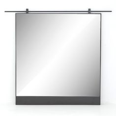 a square mirror hanging on the wall next to a black frame and metal bar around it