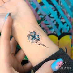 a woman's wrist with a clover tattoo on it