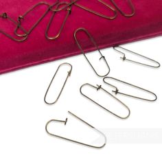 five pairs of metal hooks sitting on top of a pink velvet bag next to each other