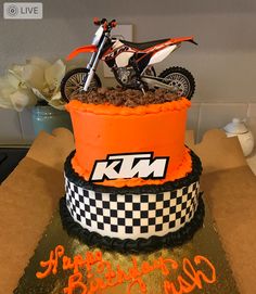 a motorcycle is on top of a cake with the words ktm written in orange