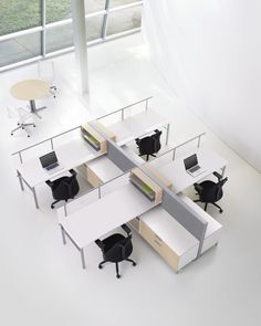 an office cubicle with four desks and two chairs in front of a large window