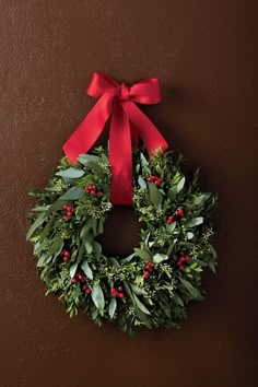 a christmas wreath hanging on the wall with a red bow