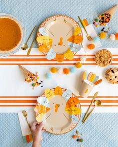 a person holding a plate with a turkey design on it next to other plates and spoons