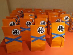 many orange bags with blue ribbon tied around them on an orange tablecloth covered table