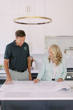 a man and woman looking at blueprint in the kitchen