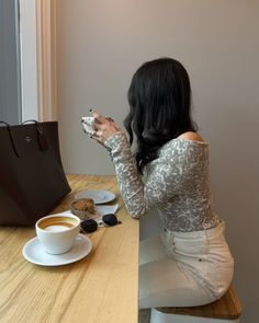 a woman sitting at a table with a cup of coffee