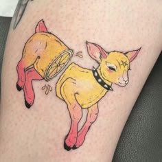 a small goat tattoo on the leg of a woman's thigh, it is yellow and red