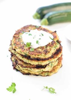 a stack of zucchini fritters topped with sour cream and parsley