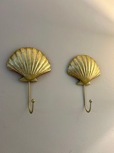 two gold scallop hooks on the wall, one is holding an umbrella and the other has a hook