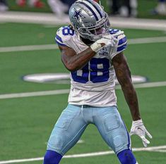 a football player holding his hands up in the air while standing on top of a field