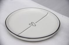 a white plate with a black line drawn on the side and a heart in the middle