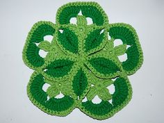 a green crocheted flower with leaves on the center and four petals in the middle