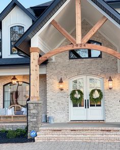 the front entrance to a house with two wreaths on it's pillars and windows