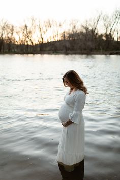 a pregnant woman standing in the water at sunset