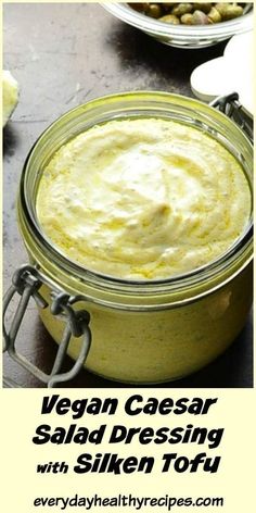 a jar filled with yellow sauce sitting on top of a table next to other dishes