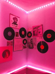 a pink room with various records on the wall and lights hanging from the ceiling above it