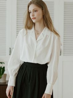 This is NONLOCAL’s blouse exudes a clean look. It's made from a soft-touch blend of rayon and cotton, offering a luxurious feel with just the right amount of flow. The subtle shirring on the shoulders and cuffs, along with the classic flat collar line, stand out. The pearl button accents on the sleeves add a feminine touch.- Ideal for daily wear- Can be paired with different bottoms to create various looks- Features back pleat detailing and brand logo symbol embroidery on the side for added flair Pearls Outfit, Pearl Outfit, Logo Symbol, Flat Collar, White Button Up, Puff Sleeve Blouse, Blouse White, Blouse Outfit, The Pearl