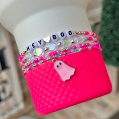 a close up of a person's hand holding a pink bag with charms on it