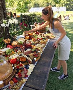 a woman standing in front of a table filled with lots of food on top of it