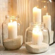 three jars filled with sand and lit candles