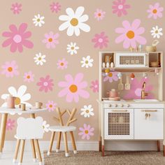 a child's playroom with pink and white flowers on the wall, wooden table and chairs