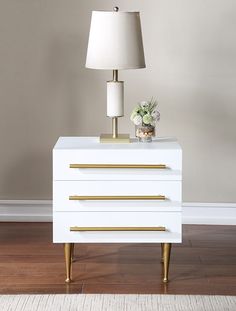 a white and gold nightstand with a lamp on top