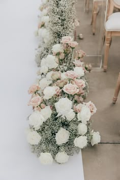 a long table with white and pink flowers on the top is set up for a wedding ceremony