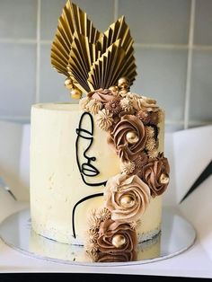 a white cake with gold decorations on top and a woman's face painted on the side