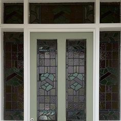 two stained glass doors in front of a green door with white trim and sidelights