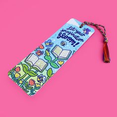 a bookmark on a pink background with an image of a book and a tassel