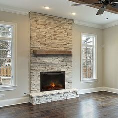 an empty living room with a fireplace and two windows