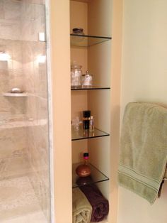 a bathroom with glass shelves and towels in it